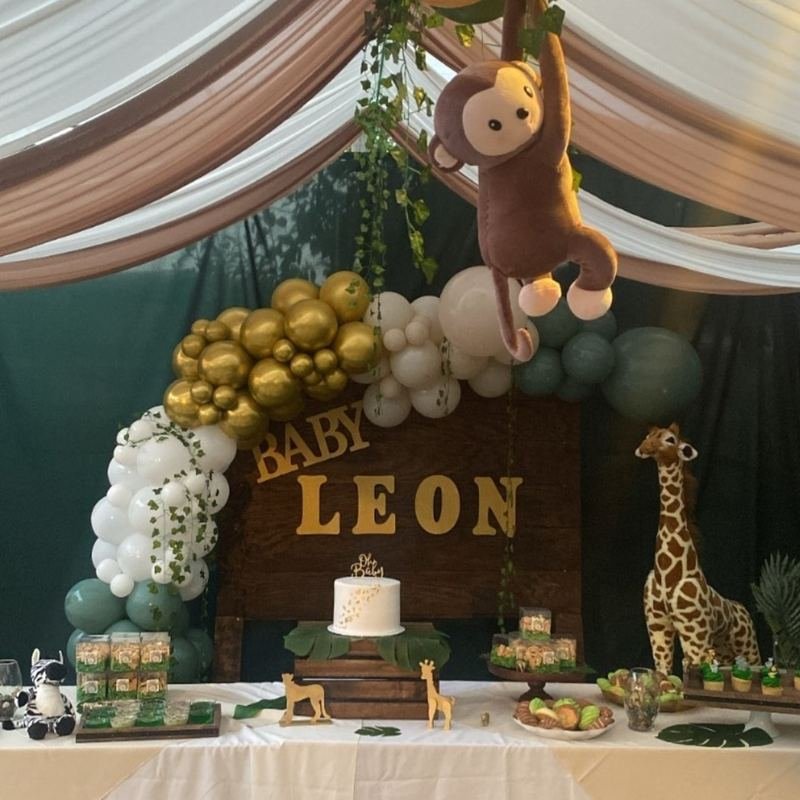 Safari baby shower table with a gold, white and sage balloon garland and a plush giraffe
