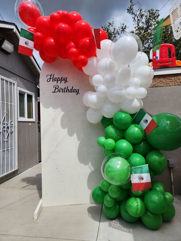 Red, white and green organic balloon garland on a white “Happy Birthday” panel with Mexican flags