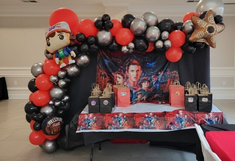 Red, black and silver balloon garland over a Stranger Things themed birthday table